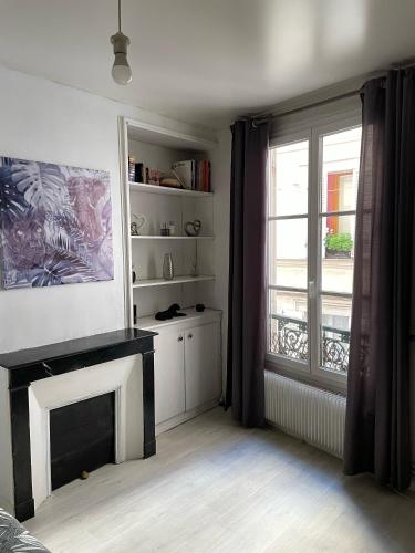 un salon avec une cheminée et une fenêtre dans l'établissement Au bas de Montmartre !, à Paris