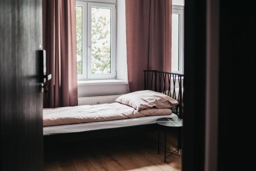 a small bed in a room with a window at Hostel Kamienica 9 in Sosnowiec