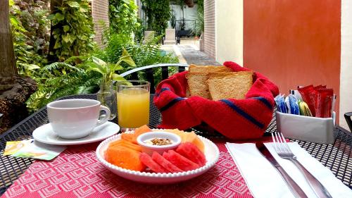 a table with a plate of bread and fruit and a cup of juice at Casa Italia Luxury Guest House - Adults Only in M&eacute;rida