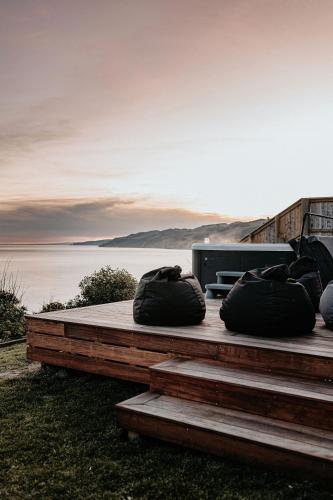 two black bags sitting on top of a wooden deck at Ocean View Bach in Motunau