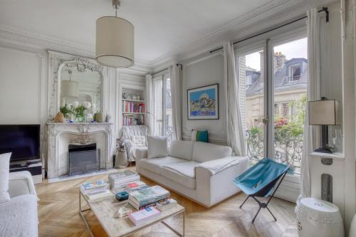 un salon avec un canapé blanc et une cheminée dans l'établissement Appartement 3 chambre Marais Paris 4, à Paris