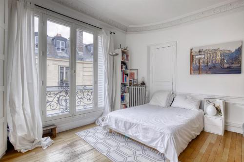 une chambre blanche avec un lit et une grande fenêtre dans l'établissement Appartement 3 chambre Marais Paris 4, à Paris
