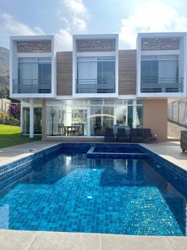 a villa with a swimming pool in front of a house at Casa Tres Ventanas de Azpitia in Santa Cruz de Flores