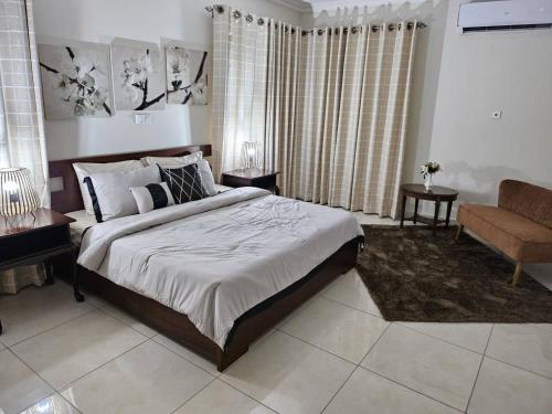 a bedroom with a bed and a couch and a chair at Summit Residence in Accra