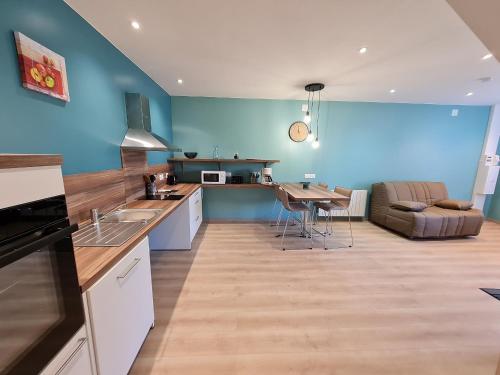 une cuisine avec des murs bleus, une table et un canapé dans l'établissement Gîte de Plain-Pied avec Confort Moderne, Nature et Loisirs à Proximité - FR-1-584-184, à Lironville