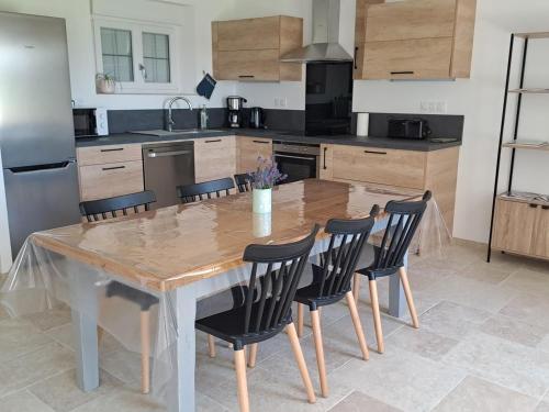 une cuisine avec une table en bois et des chaises noires dans l'établissement Maison de campagne rénovée avec terrasse, 3 chambres et équipement moderne, au cœur des collines du Perche - FR-1-410-447, à Melleray