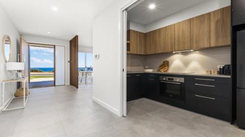 a kitchen with black cabinets and a view of the ocean at Puesta de Sol Apartment by Wine Coast Holidays in Sellicks Beach