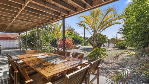 un patio esterno con tavolo e sedie in legno di Little Boat Beach House at Aldinga Beach by Wine Coast Holiday Rentals a Aldinga Beach