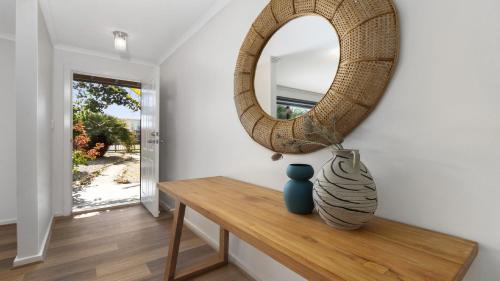 uno specchio e un vaso su un tavolo in una stanza di Little Boat Beach House at Aldinga Beach by Wine Coast Holiday Rentals a Aldinga Beach