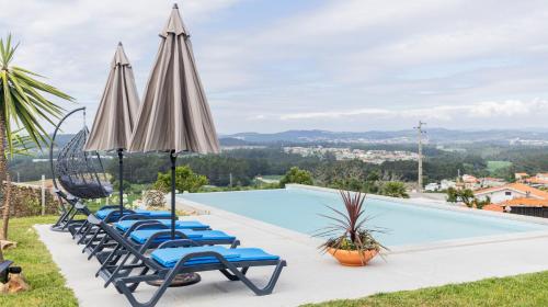 a group of lounge chairs and umbrellas next to a swimming pool at Quintinha Sao Martinho Luxury 2 Suites Villa Padrao With Sauna in Vila do Conde