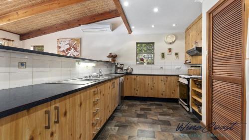a large kitchen with wooden cabinets and black counter tops at Portavino by Wine Coast Holiday Rentals in Port Willunga