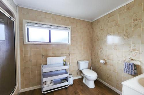 a bathroom with a toilet and a sink and a window at Cosy Hahei Retreat in Hahei