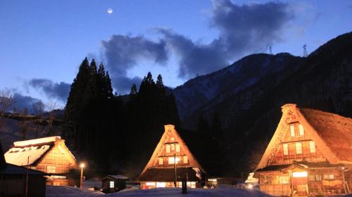 a group of buildings with mountains in the background at Gokayama Onsen Akaokan in Nanto