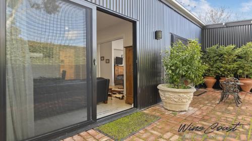WillungaHideaway Nook by Wine Coast Holiday Rentals的滑动玻璃门,通往种植了盆栽的庭院