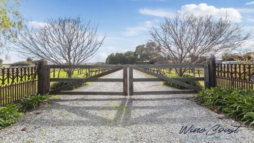 a wooden fence with a gate in a field at The Cubby House by Wine Coast Holiday Rentals in Willunga