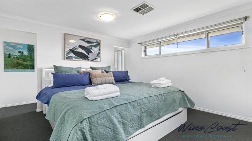 a bedroom with a large bed with towels on it at R & R Aldinga Beach by Wine Coast Holidays in Aldinga Beach