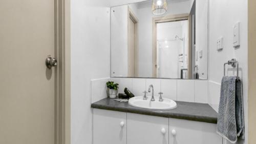a bathroom with a sink and a mirror at Sea-Vine Hideaway by Wine Coast Holiday Rentals in Port Willunga