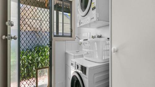 a washer and dryer in a bathroom with a window at Sea-Vine Hideaway by Wine Coast Holiday Rentals in Port Willunga