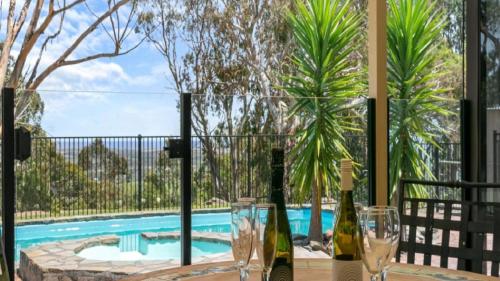 two bottles of wine sitting on a table next to a swimming pool at Southern Vales Sunsets by Wine Coast Holidays in Willunga