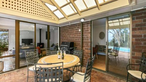 a conservatory with a table and chairs and a brick wall at Southern Vales Sunsets by Wine Coast Holidays in Willunga