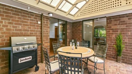 a patio with a table and a stove and a table and chairs at Southern Vales Sunsets by Wine Coast Holidays in Willunga