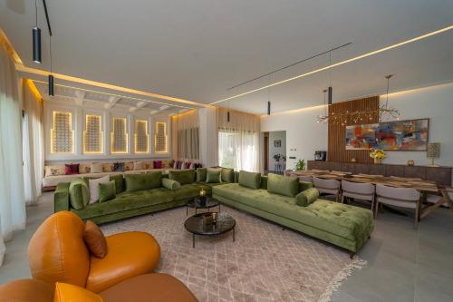 a living room with green couches and a dining room at Villa Marrakech vue atlas in Marrakech
