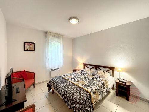 une chambre avec un lit et une chaise rouge dans l'établissement Appartement F2 climatisé à Lamalou-les-Bains, terrasse, proche centre et thermes, animaux acceptés - FR-1-451-167, à Lamalou-les-Bains
