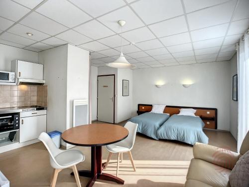 une chambre avec un lit, une table et des chaises dans l'établissement Charmant T1 avec balcons, proche thermes et centre-ville, au cœur du Parc Naturel du Haut-Languedoc - FR-1-451-175, à Lamalou-les-Bains