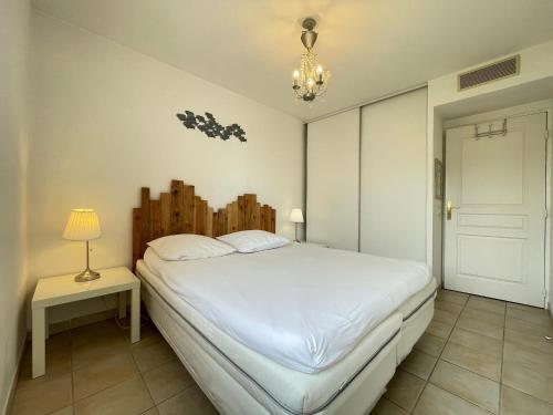 une chambre avec un lit blanc, une lampe et un lustre dans l'établissement Bel Appartement T4 à Sète avec Terrasse, Climatisation et Parking Privé - FR-1-338-571, à Sète