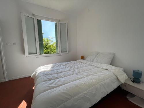 une chambre blanche avec un grand lit et une fenêtre dans l'établissement Appartement T2 rénové, climatisé, Wi-Fi, à 300m de la plage et proche commerces - Argelès-sur-Mer - FR-1-309-446, à Argelès-sur-Mer