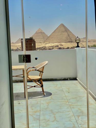 a chair on a balcony with pyramids in the background at Anubis Pyramids View in Cairo