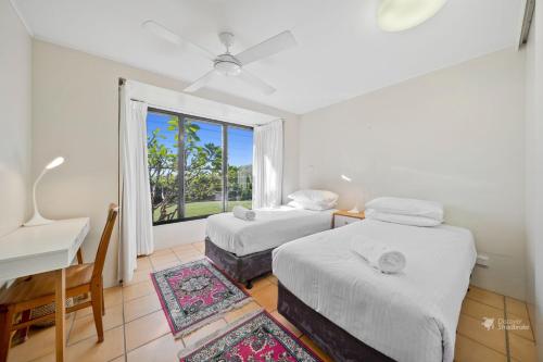 Un dormitorio con dos camas y un escritorio y una ventana. en Mintee 1 by Discover Stradbroke, en Point Lookout