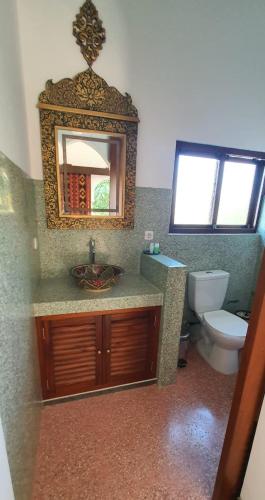 a bathroom with a sink and a toilet and a mirror at Blue Garden Boutique Hotel in Jepara