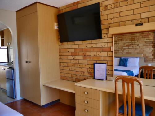 a bedroom with a bed and a tv on a brick wall at Tannum On The Beach Motel in Tannum Sands