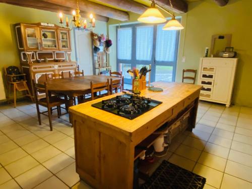 a kitchen and dining room with a stove and a table at Gîte 4 étoiles au cœur de l’Auvergne avec terrasse, jardin clos et équipements pour enfants - FR-1-582-476 in Saint-Beauzire