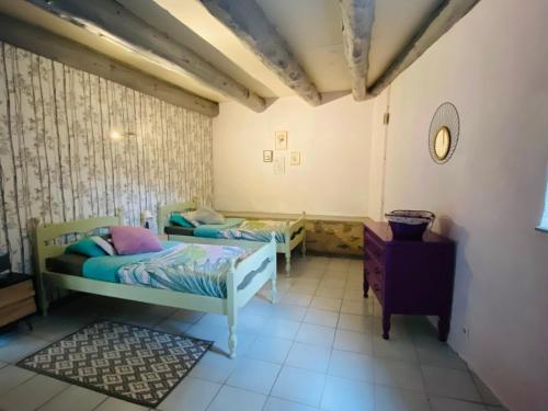 a room with two beds and a clock on the wall at Gîte 4 étoiles au cœur de l’Auvergne avec terrasse, jardin clos et équipements pour enfants - FR-1-582-476 in Saint-Beauzire