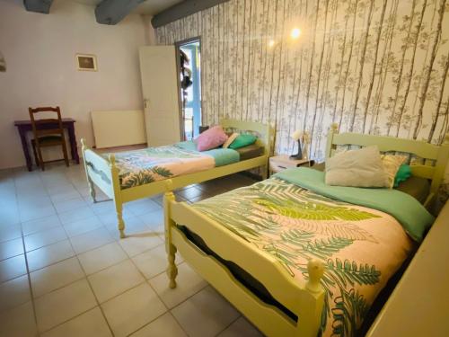 a bedroom with two beds in a room at Gîte 4 étoiles au cœur de l’Auvergne avec terrasse, jardin clos et équipements pour enfants - FR-1-582-476 in Saint-Beauzire