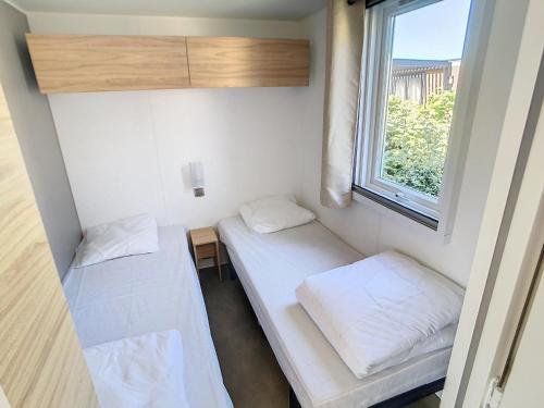 une petite chambre avec deux lits et une fenêtre dans l'établissement Mobil-home Grand Confort 2 Chambres, Proche Plage, 4 Pers., Piscine Chauffée, Parking, Wi-Fi Gratuit - FR-1-361A-86, à Jullouville