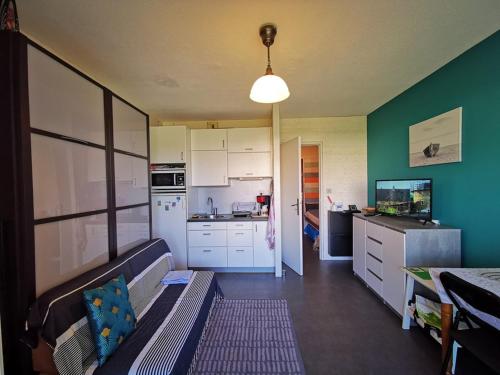 une cuisine avec des armoires blanches et un canapé dans une pièce dans l'établissement Studio calme avec loggia, proche plage et centre, climatisé, parking inclus - FR-1-803-54, au Lavandou