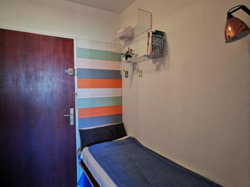 une chambre avec un lit et un mur rayé coloré dans l'établissement Studio calme avec loggia, proche plage et centre, climatisé, parking inclus - FR-1-803-54, au Lavandou