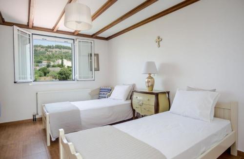 two beds in a white room with a window at Pantheon Villa Svoronata in Svoronata
