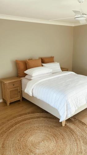 a bedroom with a large white bed and a night stand at HOME ByCoastalRoad in Toukley