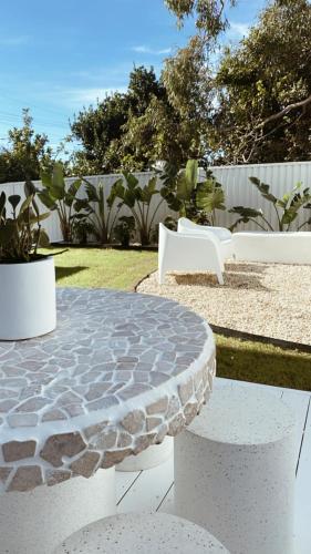 a patio with a stone table and white benches at HOME ByCoastalRoad in Toukley