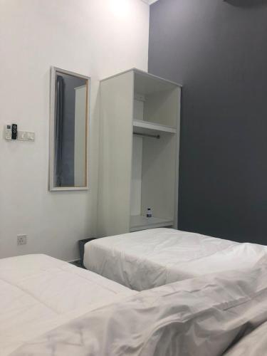 two white beds in a room with a mirror at Calma Villa Hutan Kampung in Alor Setar