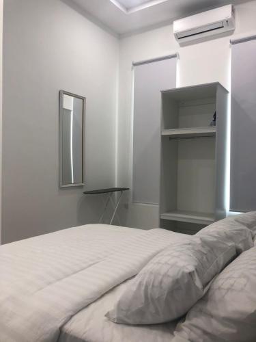 a white bedroom with a bed and a mirror at Calma Villa Hutan Kampung in Alor Setar