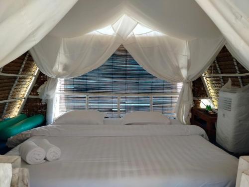 a bedroom with two white beds and a window at Madu Tiga Beach and Resort in Tanjung Pinang 