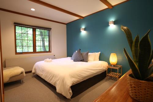 une chambre avec un grand lit et une plante dans l'établissement Jumoku, à Hakuba