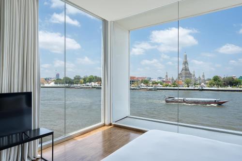 a bedroom with a large window with a view of the river at Sala Rattanakosin Bangkok in Bangkok