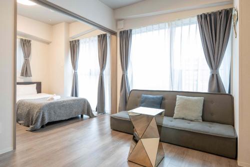 een woonkamer met een bank en een bed bij Regale Dotonbori East in Osaka