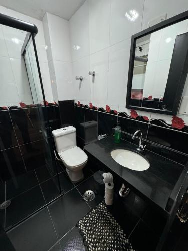 a black and white bathroom with a toilet and a sink at Apartamento Sunset House Porchat in São Vicente